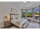 Bright main bedroom featuring hardwood floors, a ceiling fan, and a bay window overlooking lush greenery at 16406 Chapman Crossing Dr, Lithia, FL 33547