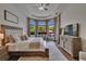 Bright main bedroom featuring hardwood floors, a ceiling fan, and a bay window overlooking lush greenery at 16406 Chapman Crossing Dr, Lithia, FL 33547