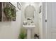 Stylish powder room with a pedestal sink, round mirror, and decorative wreath at 2234 Lennox Dale Ln, Brandon, FL 33510