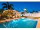 A backyard oasis, showcasing a sparkling pool, illuminated pergola and relaxing lounge area for evening enjoyment at 2401 66Th S Ave, St Petersburg, FL 33712