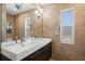 Bathroom with a modern floating double sink vanity, wall mirror and tan stone tiled walls at 261 Kentucky Ave, Crystal Beach, FL 34681
