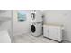 Laundry room with stacked washer and dryer, white cabinets and drawers, and a window at 261 Kentucky Ave, Crystal Beach, FL 34681