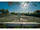 View of a tennis court with shade trees and a covered bench at 29903 Baywood Ln, Wesley Chapel, FL 33543