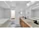 Well-lit bathroom featuring dual sinks, a large mirror, and a tub with decorative tile accents at 30 Pinetree Ct, Palm Harbor, FL 34683