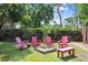 Cozy backyard fire pit area with red Adirondack chairs, perfect for outdoor entertaining at 3440 Crenshaw Lake Rd, Lutz, FL 33548
