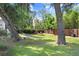 Relaxing backyard setting with a hammock strung between trees, and red Adirondack chairs around a fire pit at 3440 Crenshaw Lake Rd, Lutz, FL 33548