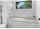 Bright bathroom featuring a soaking tub with marble surround and a window view at 3440 Crenshaw Lake Rd, Lutz, FL 33548