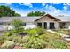 A charming single-story home with a metal roof and front garden filled with blooming plants at 3440 Crenshaw Lake Rd, Lutz, FL 33548
