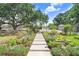 A stone walkway lined with flowers leads to a beautiful home, complemented by a large shade tree at 3440 Crenshaw Lake Rd, Lutz, FL 33548