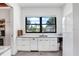 A bright modern kitchen features a large window with views of the yard and white cabinets at 3440 Crenshaw Lake Rd, Lutz, FL 33548