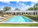 Large, sparkling pool with surrounding green space and a view of the home's expansive, modern exterior at 3440 Crenshaw Lake Rd, Lutz, FL 33548