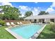 Relaxing pool area with chaise lounges, manicured lawn, and view of the modern home's stylish exterior and covered patio at 3440 Crenshaw Lake Rd, Lutz, FL 33548