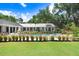 Beautiful backyard pool with manicured lawn, decorative grasses, and home exterior with full outdoor seating arrangement at 3440 Crenshaw Lake Rd, Lutz, FL 33548