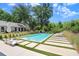 Inviting pool area with chaise lounges and grass accents with view of white home exterior and lush landscaping at 3440 Crenshaw Lake Rd, Lutz, FL 33548