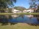 Waterfront villa community view across a tranquil pond with mature trees and sunny skies at 3505 Tarpon Woods Blvd # P408, Palm Harbor, FL 34685