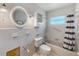 Clean bathroom featuring white tile, a bathtub with shower, and a large, round mirror at 365 La Hacienda Dr, Indian Rocks Beach, FL 33785