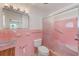 Bathroom featuring a pink tile shower with a glass door, white toilet, and updated lighting fixtures at 365 La Hacienda Dr, Indian Rocks Beach, FL 33785