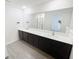 Modern bathroom featuring dual sinks, a large mirror, and sleek gray wood-look flooring at 5310 Companion Ln, Tampa, FL 33619