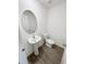 Half-bath featuring a modern pedestal sink, an oval mirror, and wood-look floors at 5310 Companion Ln, Tampa, FL 33619