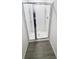Modern shower with glass door and sleek gray wood-look flooring at 5310 Companion Ln, Tampa, FL 33619