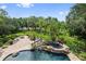 An enticing pool and waterfall feature create a tranquil backyard retreat surrounded by lush greenery at 6310 W Maclaurin Dr, Tampa, FL 33647