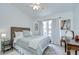 Bright bedroom features light wood floors, white walls, a ceiling fan and a comfortable bed with patterned linens at 7107 Colonial Lake Dr, Riverview, FL 33578