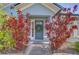 Charming blue front door with a wreath, flanked by vibrant red foliage and a paved walkway at 7107 Colonial Lake Dr, Riverview, FL 33578