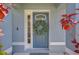 Elegant blue front door with decorative wreath and sidelight, framed by lush greenery at 7107 Colonial Lake Dr, Riverview, FL 33578