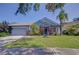 Charming blue single-story home boasting a well-manicured lawn and lush, tropical landscaping at 7107 Colonial Lake Dr, Riverview, FL 33578
