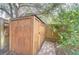 Wooden storage shed with a metal roof, surrounded by greenery and a brick pathway at 7107 Colonial Lake Dr, Riverview, FL 33578