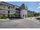 Condo building featuring neutral stucco, black iron railings, and mature landscaping creating a welcoming curb appeal at 712 Cordova Greens # 712, Largo, FL 33777
