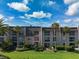 Condominium exterior with well-manicured landscaping, palm trees, and a neatly kept lawn, all under a bright, sunny sky at 712 Cordova Greens # 712, Largo, FL 33777