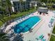 Aerial view of a large, inviting community pool with lounge chairs, lush landscaping, and a nearby cabana area at 712 Cordova Greens # 712, Largo, FL 33777