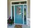 Close-up of the detailed teal front door, complete with sidelights, a transom window, and a welcoming floral mat at 7635 N 55Th N St, Pinellas Park, FL 33781