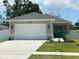 Charming single-story home featuring an attached two-car garage, a teal front door, and well-maintained landscaping at 7635 N 55Th N St, Pinellas Park, FL 33781