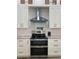 Close-up of the kitchen's stainless steel range and hood, complemented by white cabinets and granite countertops at 7635 N 55Th N St, Pinellas Park, FL 33781