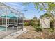 Backyard with an enclosed patio, small storage shed and tropical landscaping at 811 Woodley Rd, Clearwater, FL 33764