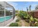 Landscaped backyard with a pathway leading to a pool and enclosed patio at 811 Woodley Rd, Clearwater, FL 33764