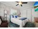 Bright bedroom with palm wallpaper, a ceiling fan, and a comfortable bed with blue accents at 811 Woodley Rd, Clearwater, FL 33764