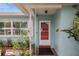 Inviting front entry with a modern white door and lush tropical landscaping at 811 Woodley Rd, Clearwater, FL 33764