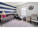 Bedroom with blue and white striped accent wall, crib, and leather chaise lounge at 8891 Bower Bass Cir, Wesley Chapel, FL 33545