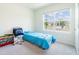 Bedroom with a blue bedspread, a gray chair, and a window with a view of the neighborhood at 8891 Bower Bass Cir, Wesley Chapel, FL 33545