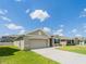 Well-maintained home featuring a spacious driveway, two-car garage, and lush green lawn, creating a welcoming exterior at 8891 Bower Bass Cir, Wesley Chapel, FL 33545
