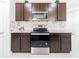 Well-equipped kitchen with stainless steel oven, microwave, granite countertops, and dark wood cabinets at 8891 Bower Bass Cir, Wesley Chapel, FL 33545