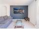 Cozy living room with a comfortable gray sofa, stylish glass tables, and a modern art piece on a painted accent wall at 8891 Bower Bass Cir, Wesley Chapel, FL 33545