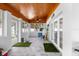 Enclosed sunroom with wooden ceiling, gray tile floors, and turf rugs at 100 18Th Nw St, Ruskin, FL 33570
