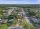 Wide aerial view of a neighborhood with mature trees, single-Gathering homes, and a lake in the distance at 12817 Lake Tree Ln, Hudson, FL 34669