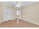 Neutral bedroom features ceiling fan, closet, and view to next room with tan walls at 12817 Lake Tree Ln, Hudson, FL 34669
