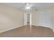 Neutral bedroom features ceiling fan, closet, and view to next room with tan walls at 12817 Lake Tree Ln, Hudson, FL 34669