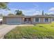 Charming single-story home featuring a well-manicured lawn, shutters, and an attached garage at 12817 Lake Tree Ln, Hudson, FL 34669